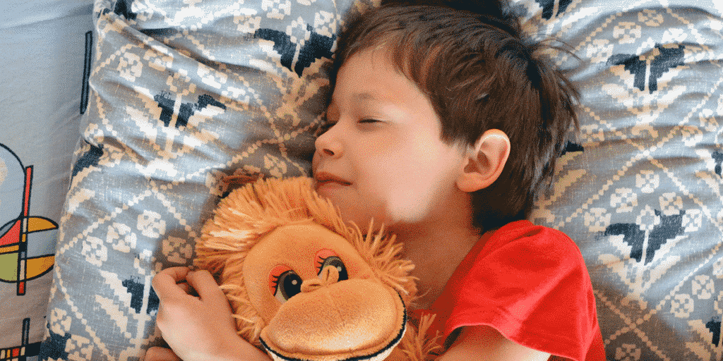 menino dormindo abraçado a bicho de pelúcia tem enurese infantil e precisa de urologista pediátrico